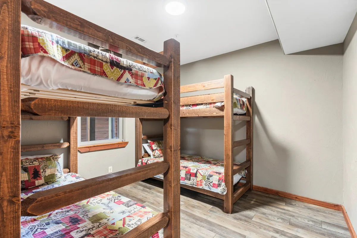 This image captures a cheerful bunk room with double twin bunk beds, colorful bedding, and a window providing natural light. The arrangement emphasizes a playful, welcoming atmosphere ideal for children or group sleepovers.