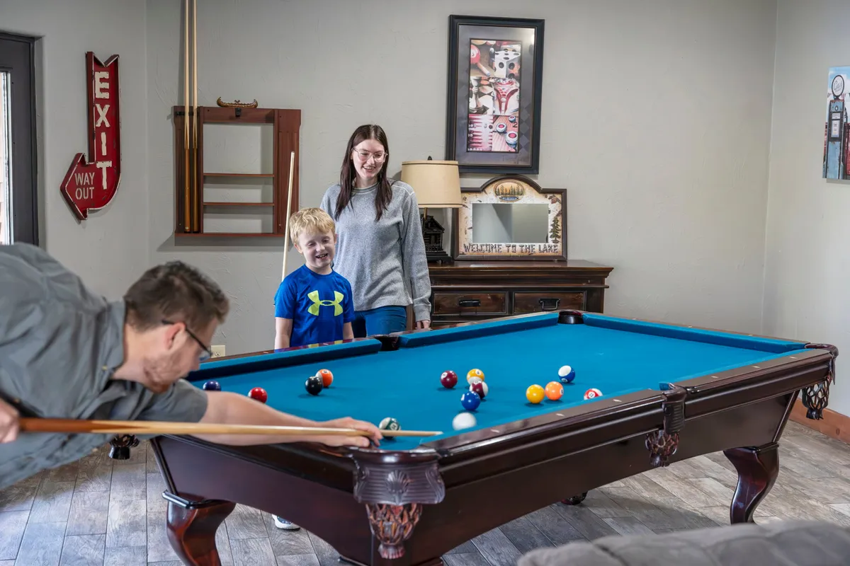 A playful family pool table scene with family members engaged in a friendly game, decorative wall art adding a personal touch, and a warm, relaxed ambiance ideal for family bonding and playful competition.