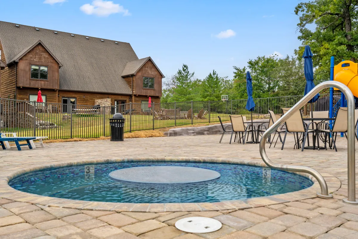 A cheerful outdoor scene featuring the swimming pool, a bubbling hot tub, a children’s slide, patio seating, and a spacious yard perfect for family and pet play. The mood is lively yet relaxed, suggesting endless opportunities for both excitement and downtime.