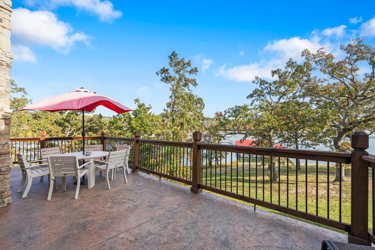 A scenic outdoor dining area with a red umbrella sits beside the lake, surrounded by trees. The tranquil ambiance and open space create a welcoming spot for pet owners to relax and enjoy the outdoors together.